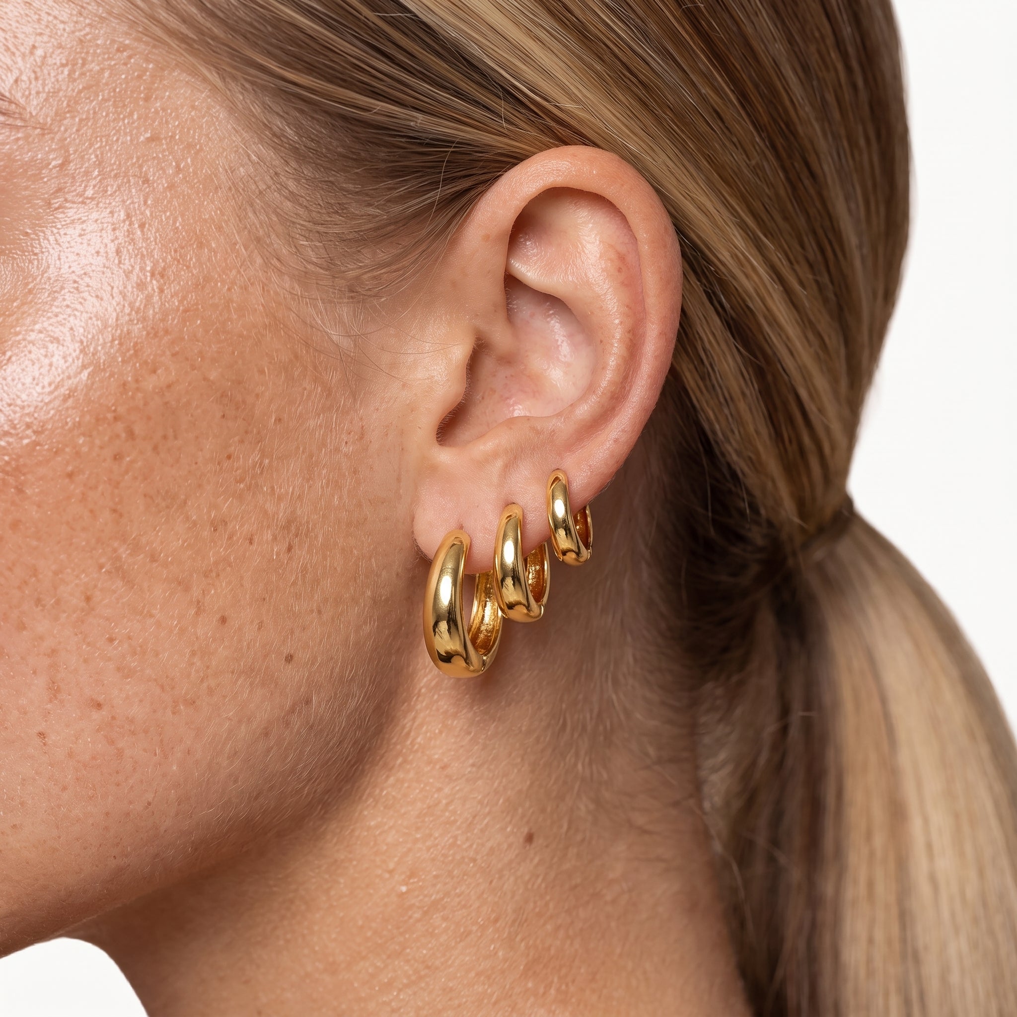 Gold-tone chunky hoop earrings worn stacked in one ear