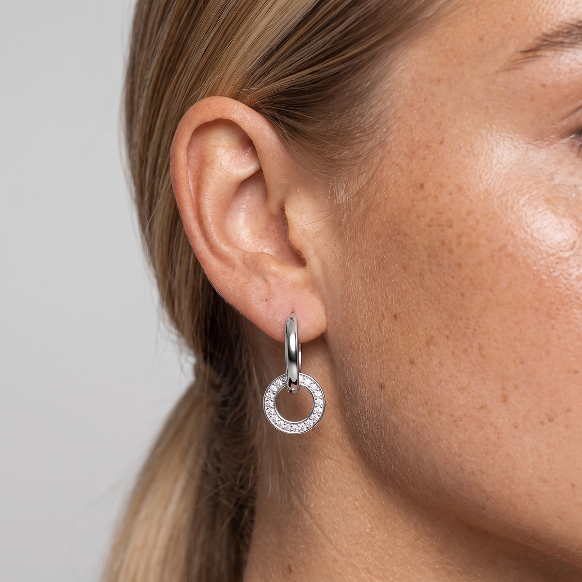 Silver-tone interlocking hoop earring worn in the ear