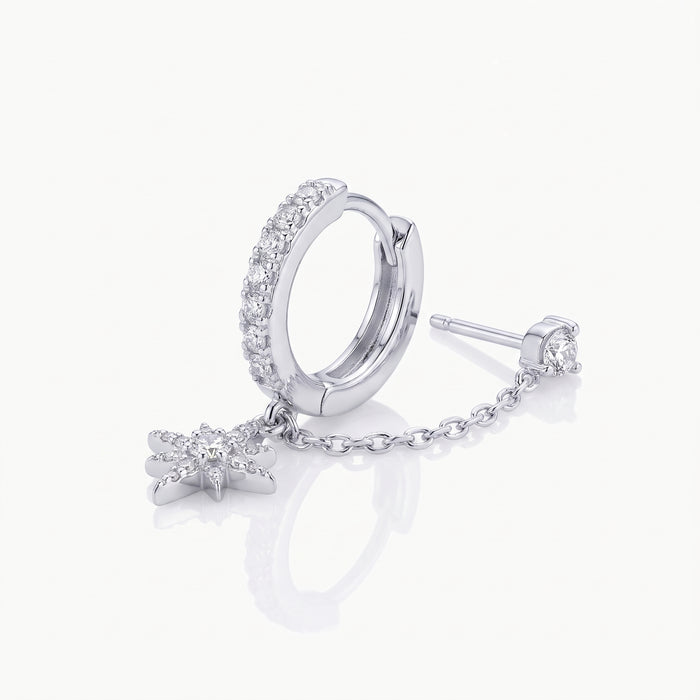 Close-up of a silver-tone chained huggie earring with star charm