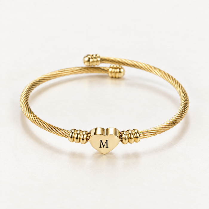 Gold-tone initial cuff bangle with letter M heart charm, angled view