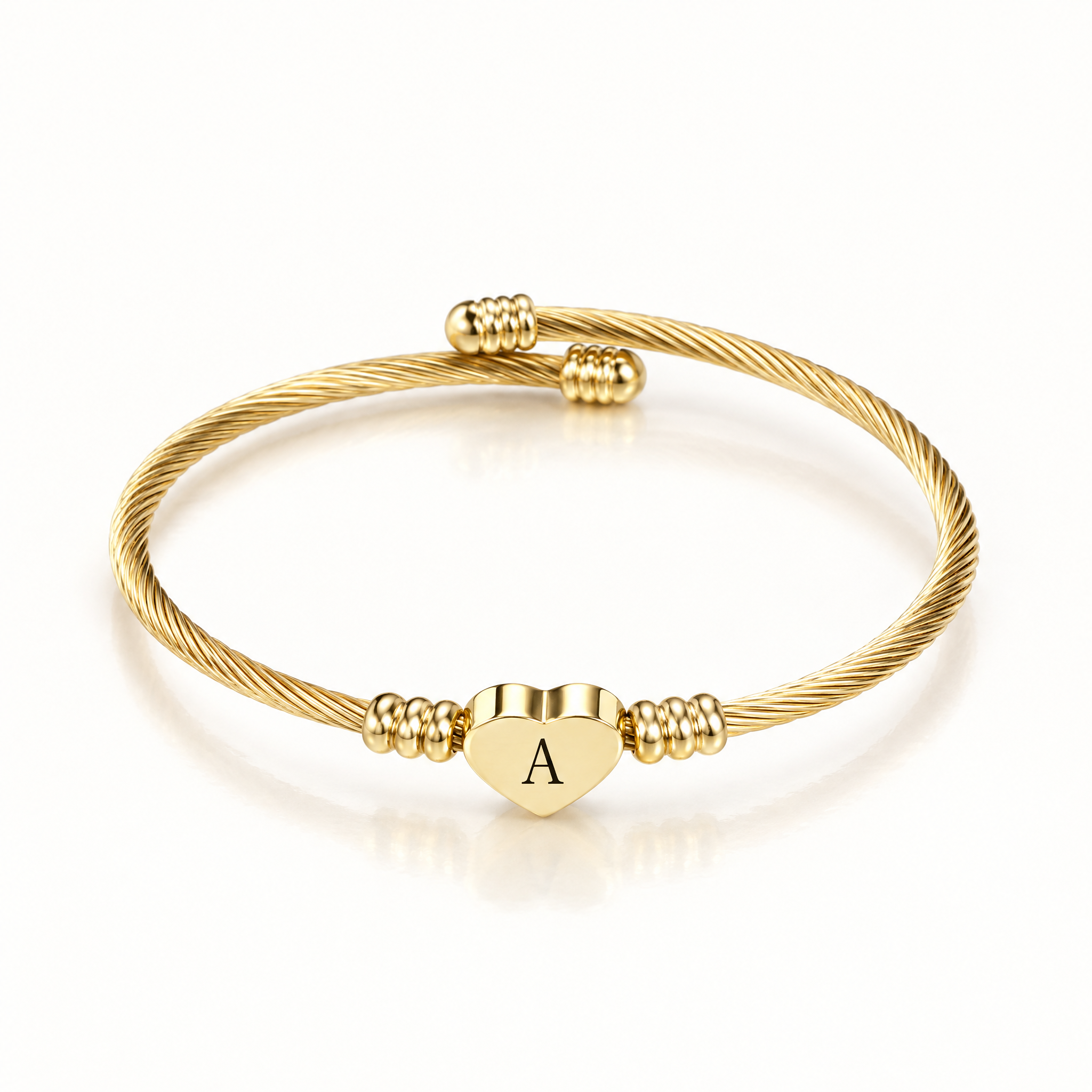 Gold-tone twisted cuff bangle with a heart charm engraved with the letter A