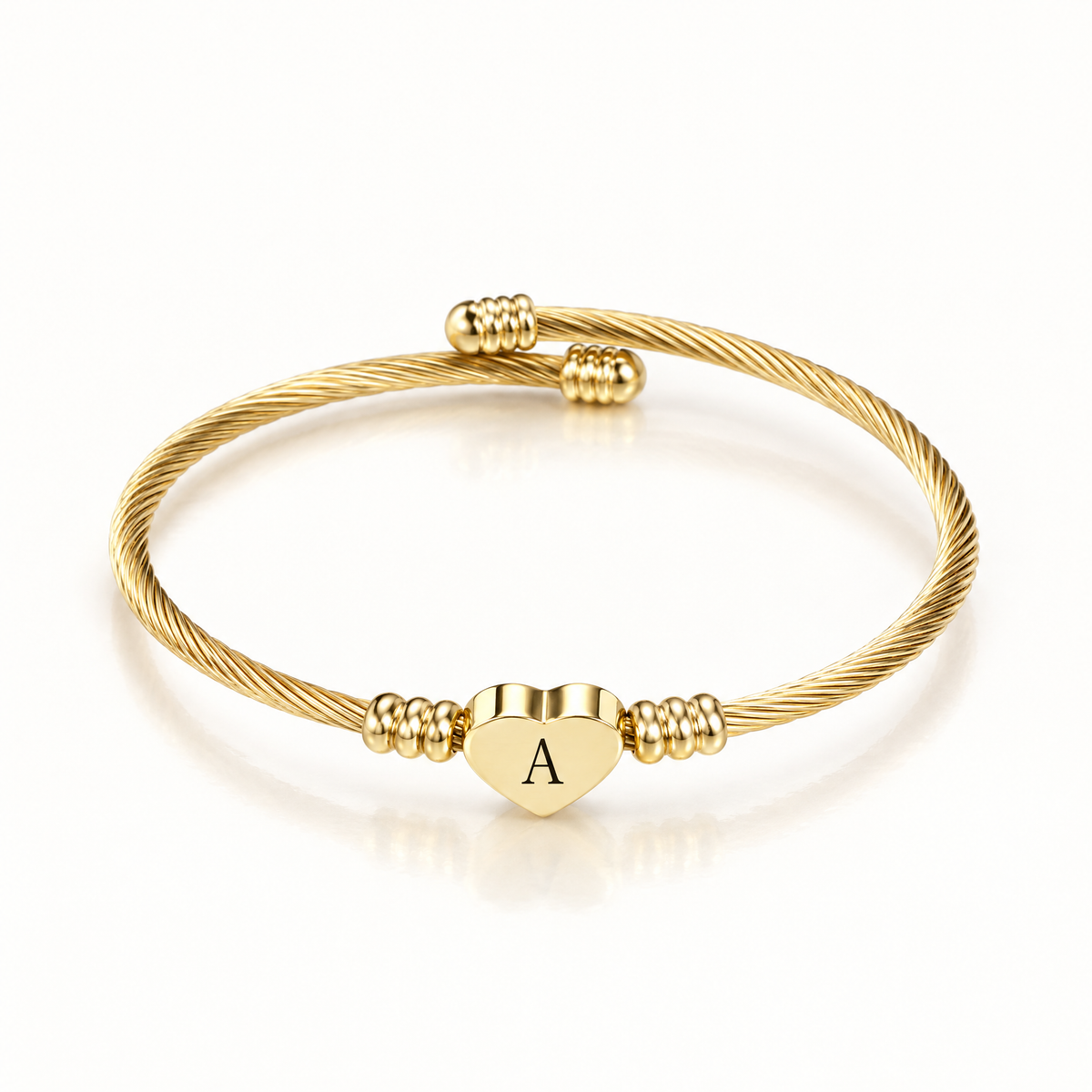 Gold-tone twisted cuff bangle with a heart charm engraved with the letter A