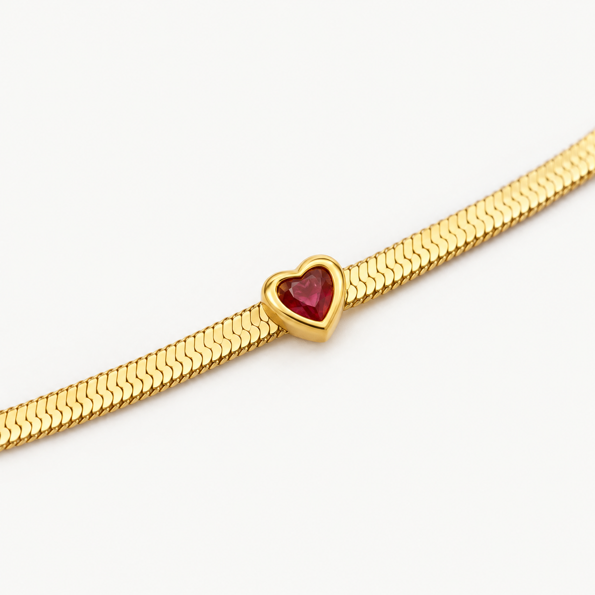 Close up of the red heart birthstone on the herringbone snake chain
