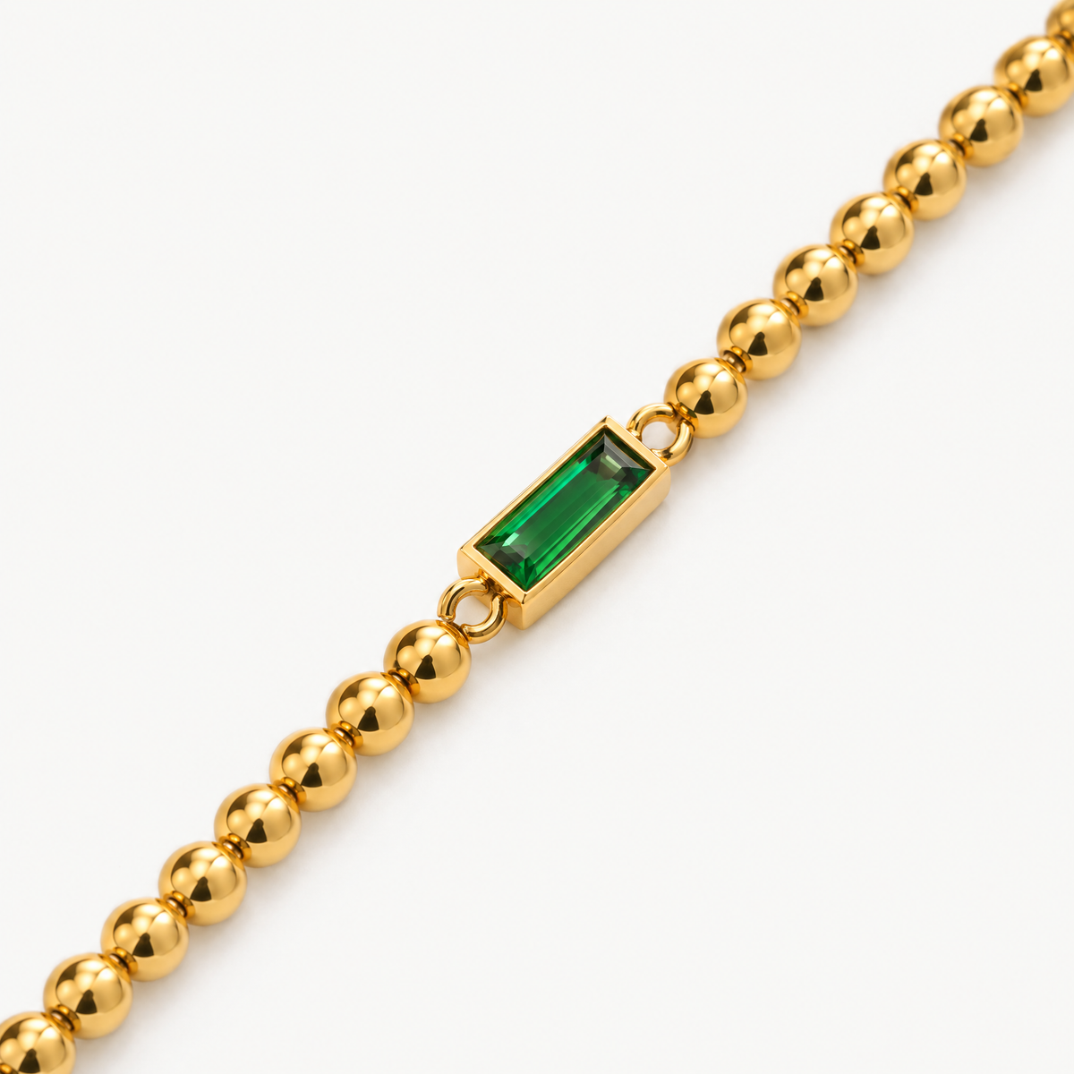 Close up of the green baguette stone between gold-tone beads