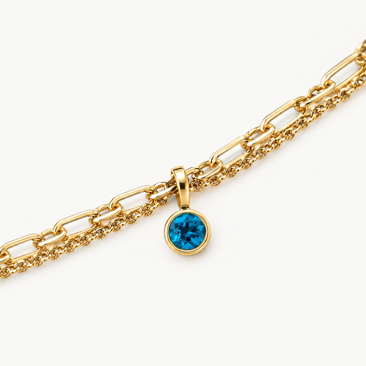Close up of the round blue birthstone charm on the paperclip chain
