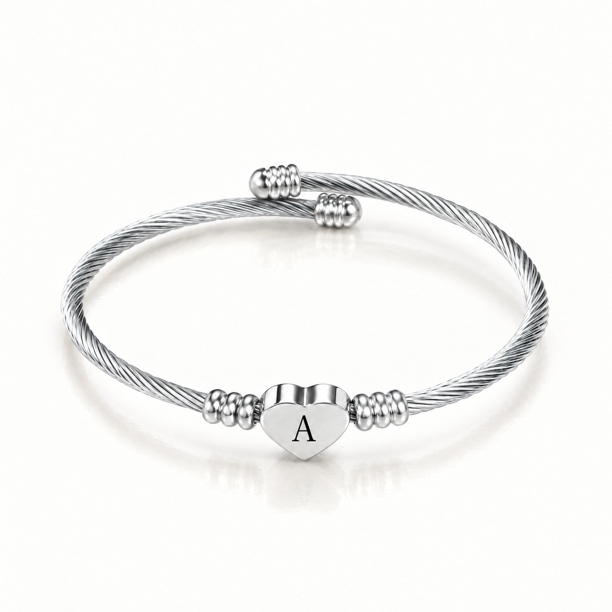 Silver-tone initial cuff bangle shown with different engraved letters on the heart charm