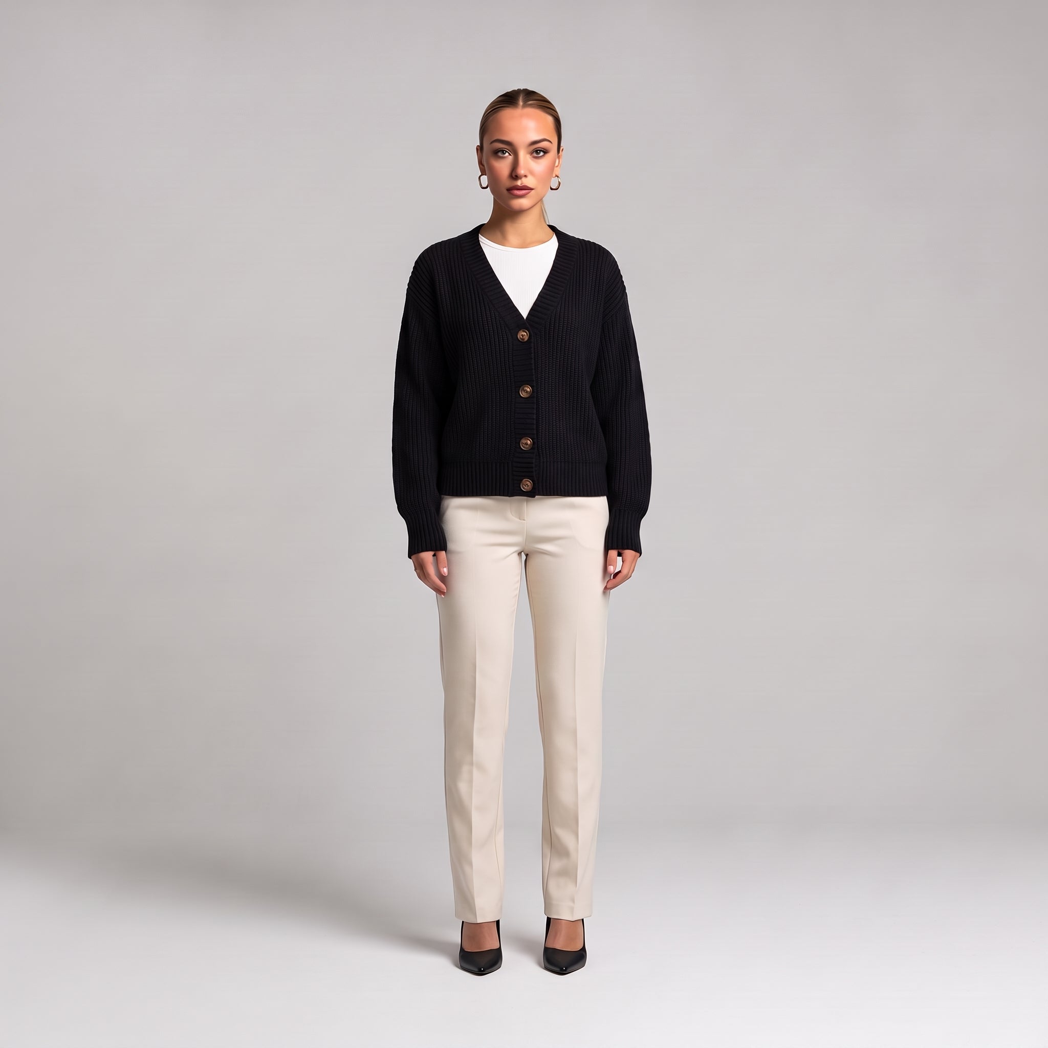 Black chunky knit cardigan worn open over a white top, full length front view