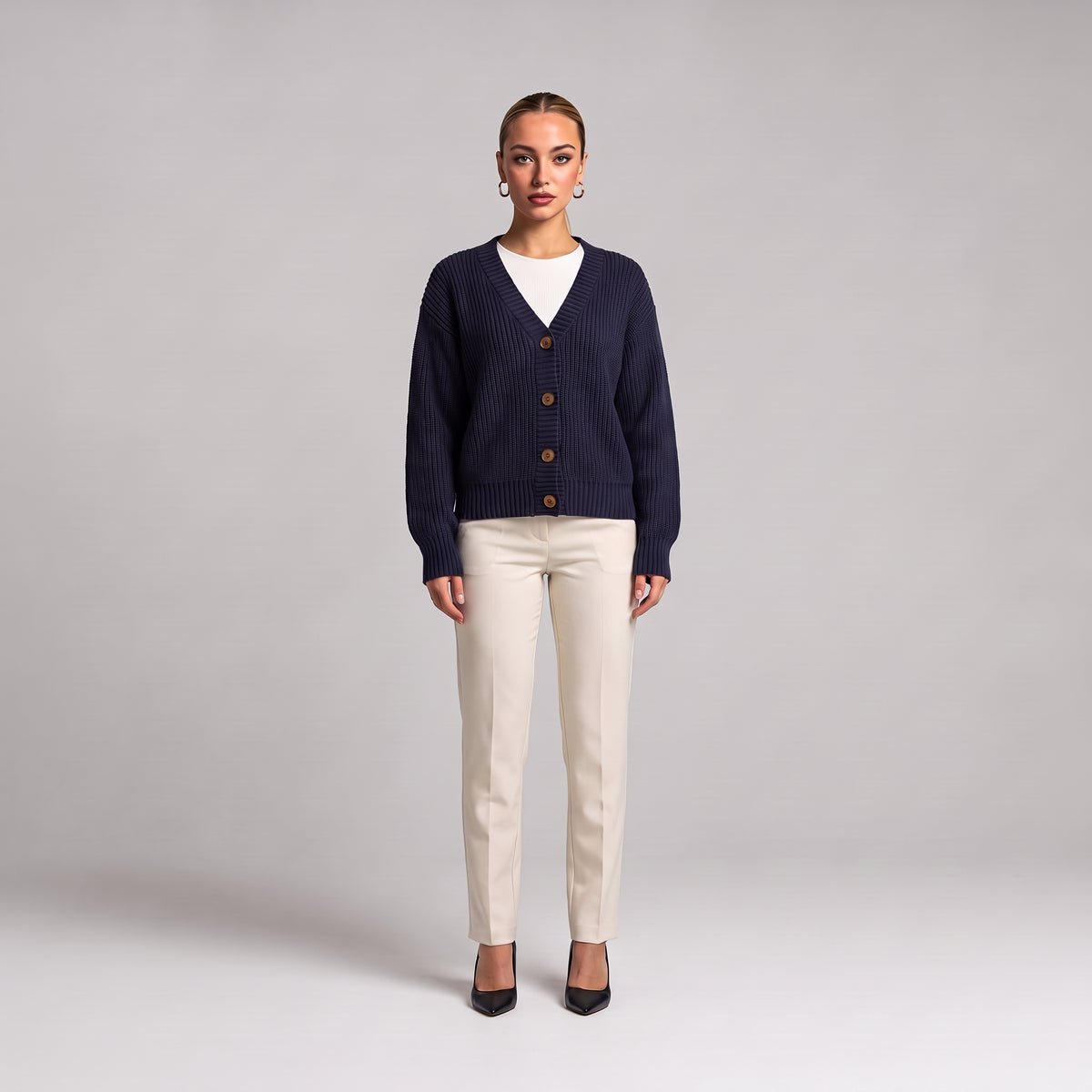 Navy chunky knit cardigan worn open over a white top, full length front view