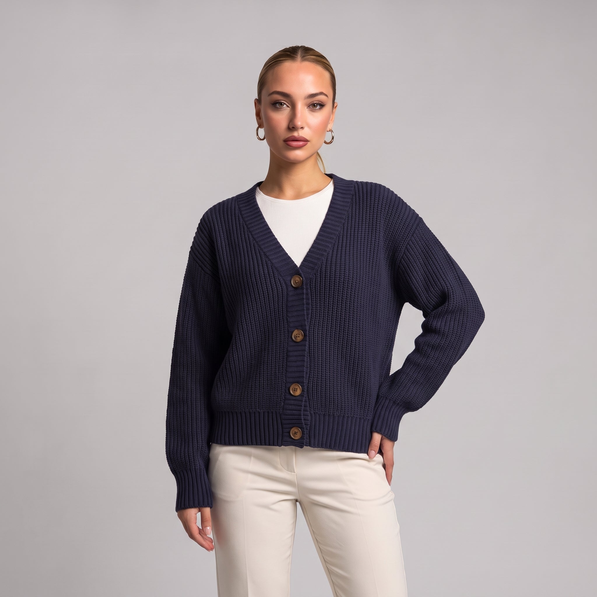 Navy chunky knit cardigan worn open over a white top, half body front view