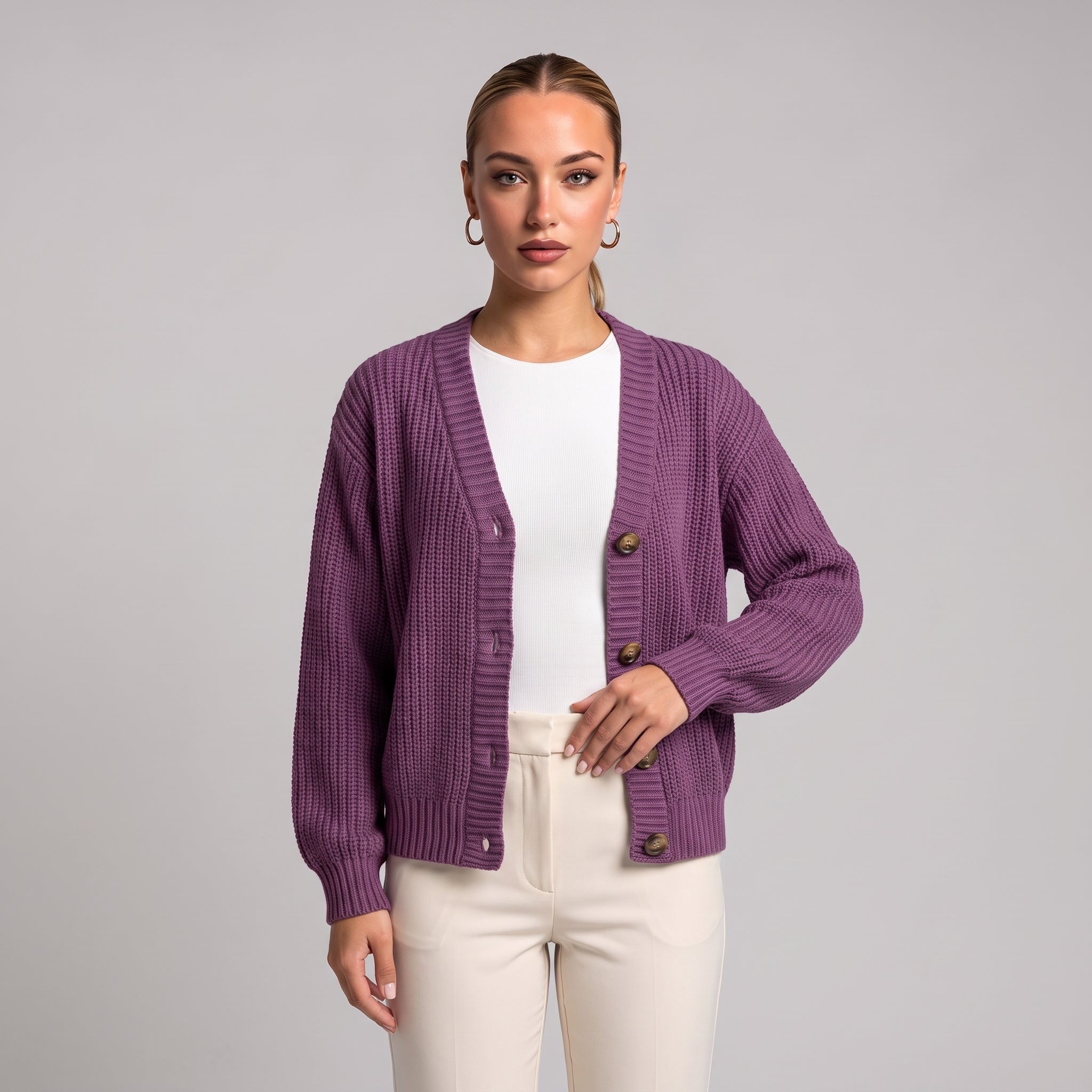 Purple chunky knit cardigan worn open over a white top, half body front view