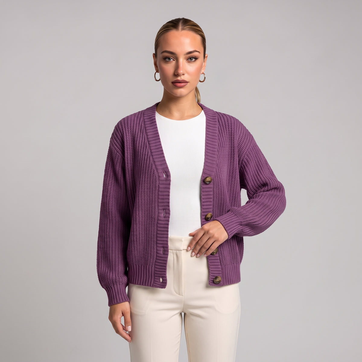 Purple chunky knit cardigan worn open over a white top, half body front view