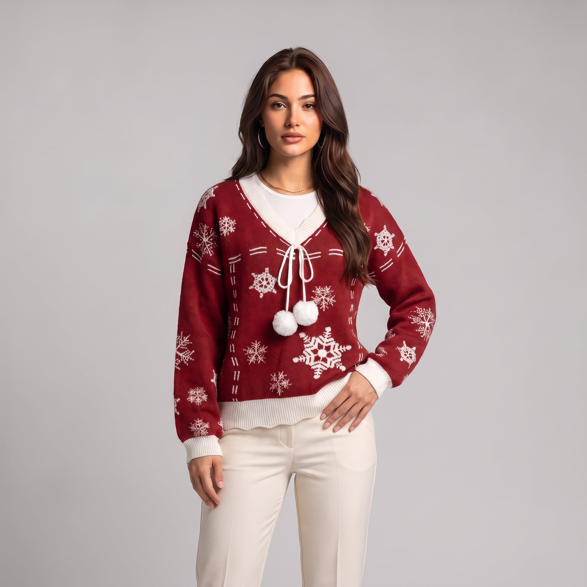 Close-up of red snowflake knit jumper with white V neck trim and pom poms