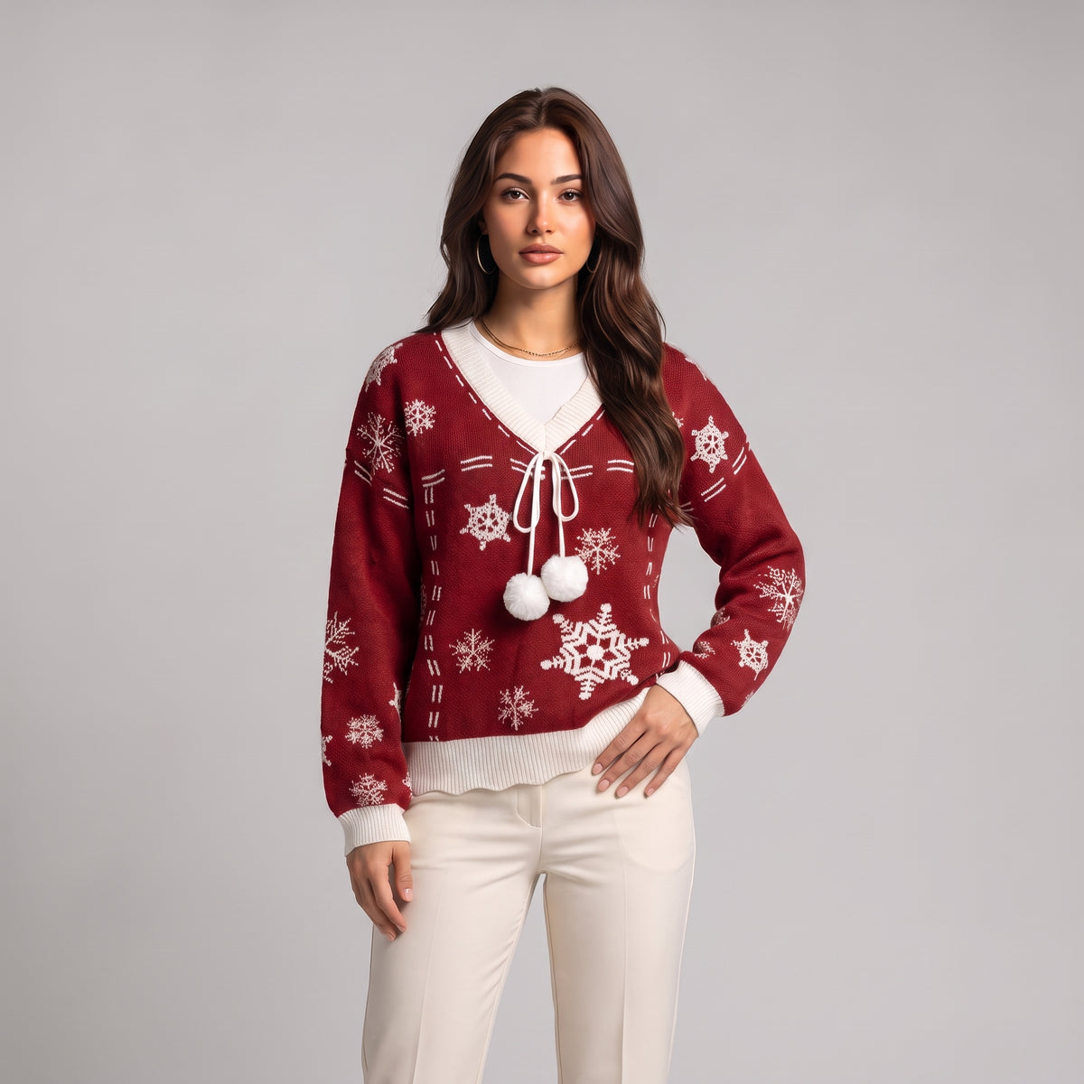Close-up of red snowflake knit jumper with white V neck trim and pom poms