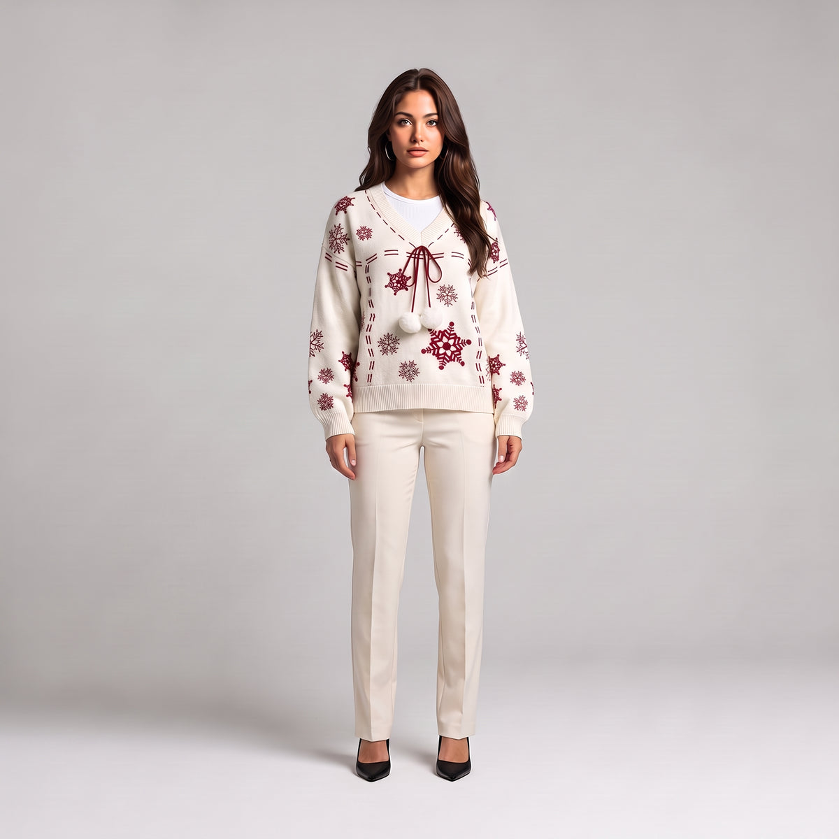 White snowflake Christmas jumper with red pom pom tie, front view on model