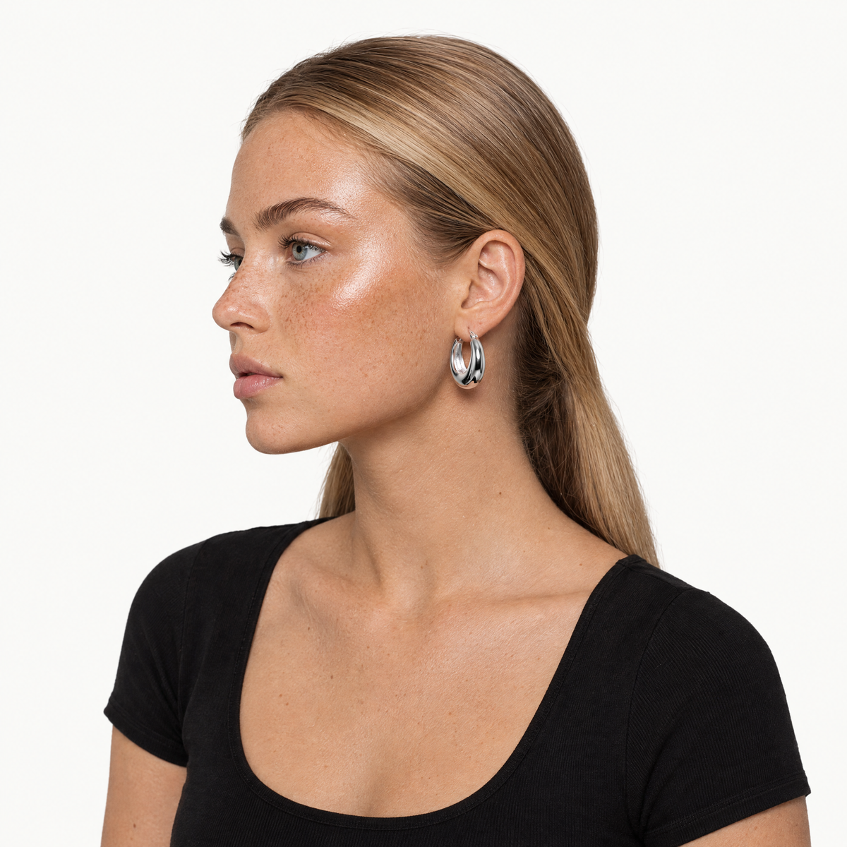 Silver-tone chunky tapered hoop earring worn by a model, shown with head and shoulders