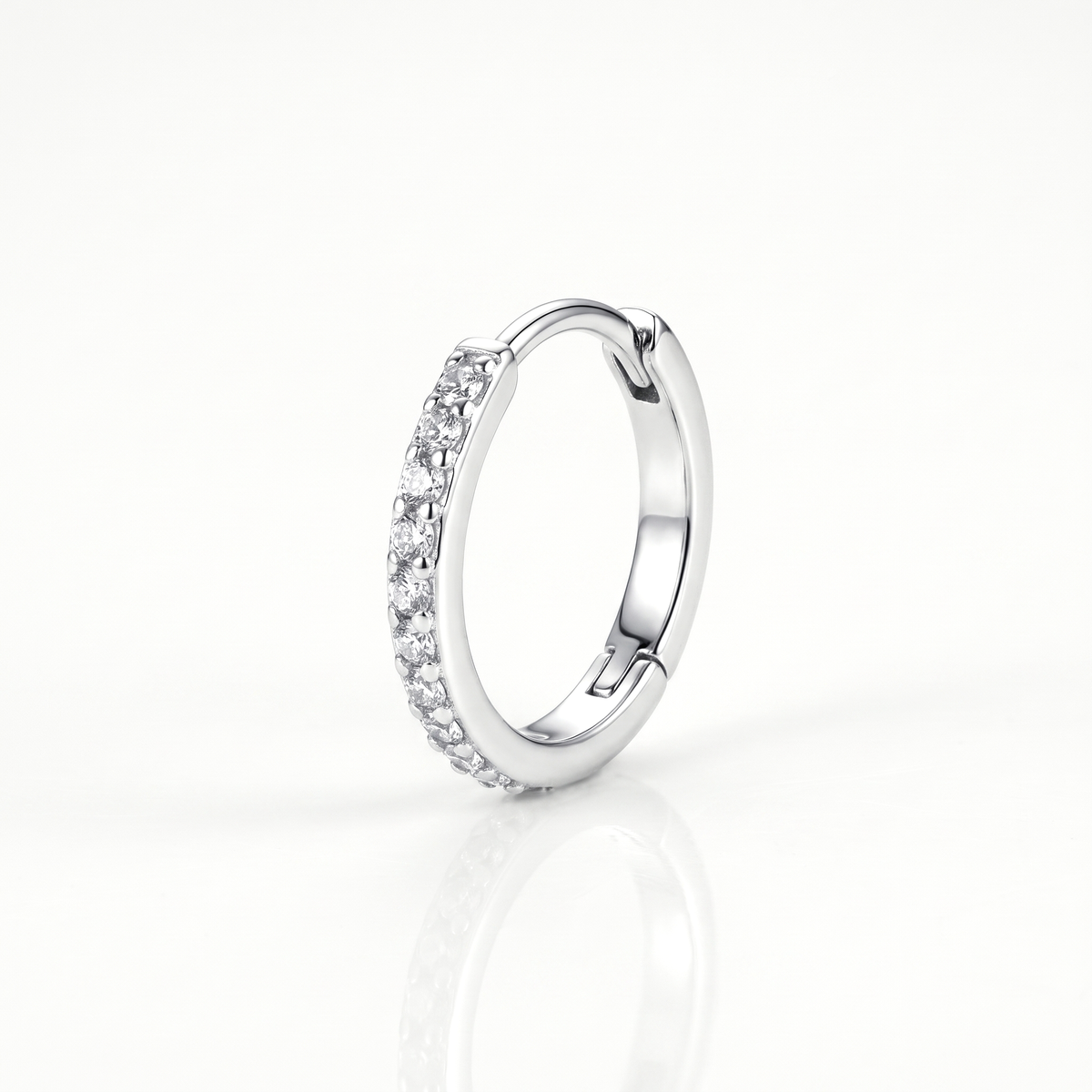 Close-up of a silver-tone huggie hoop earring with a row of clear crystal stones and hinged closure