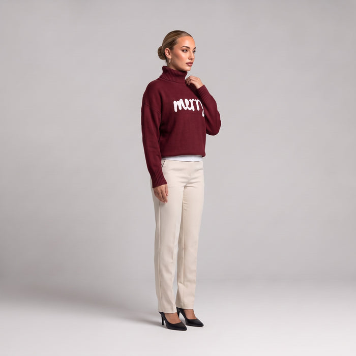 Burgundy merry roll neck Christmas jumper, side view worn with cream trousers