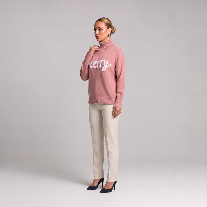 Pink merry roll neck Christmas jumper, side view worn with cream trousers