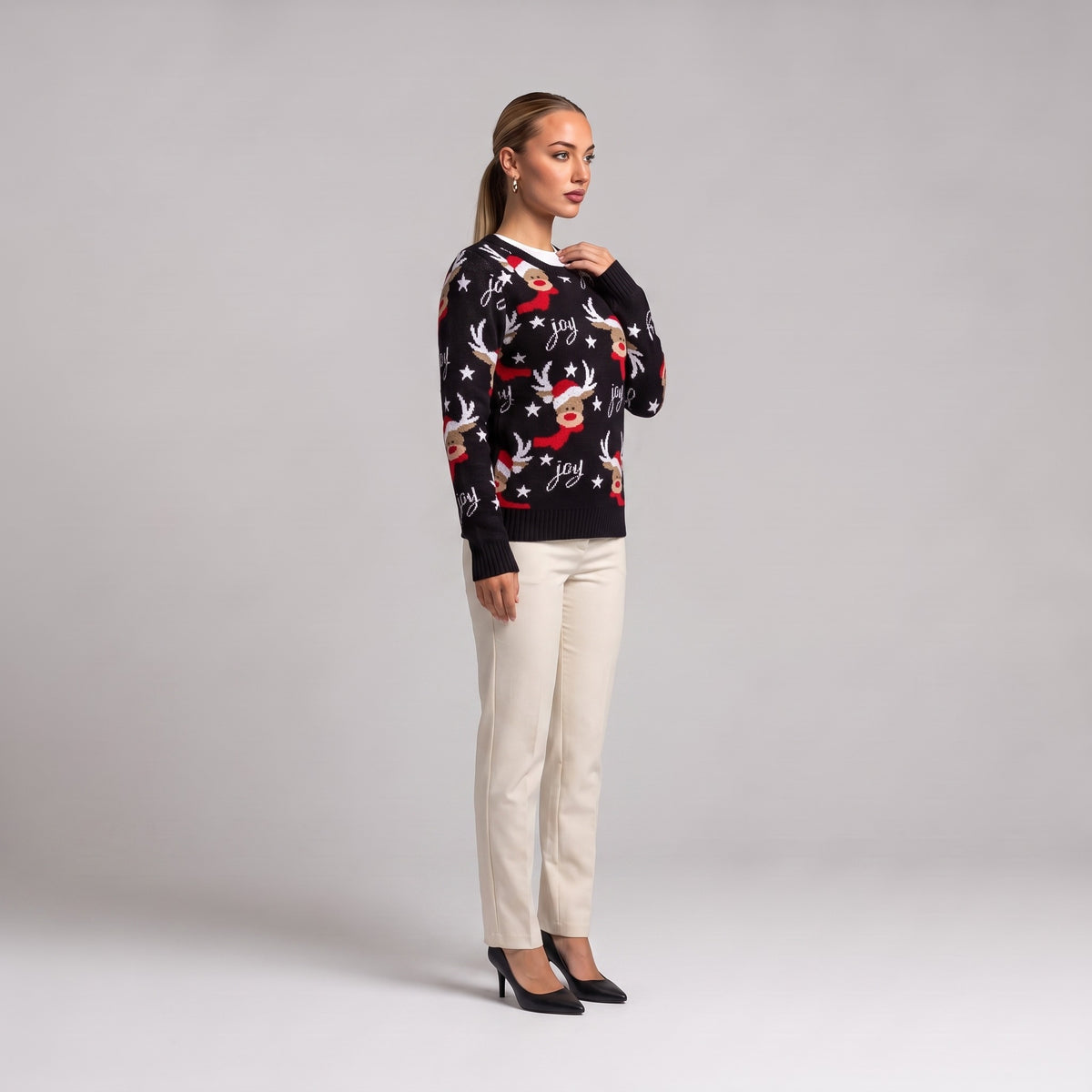 Black joy reindeer Christmas jumper, side view worn with cream trousers