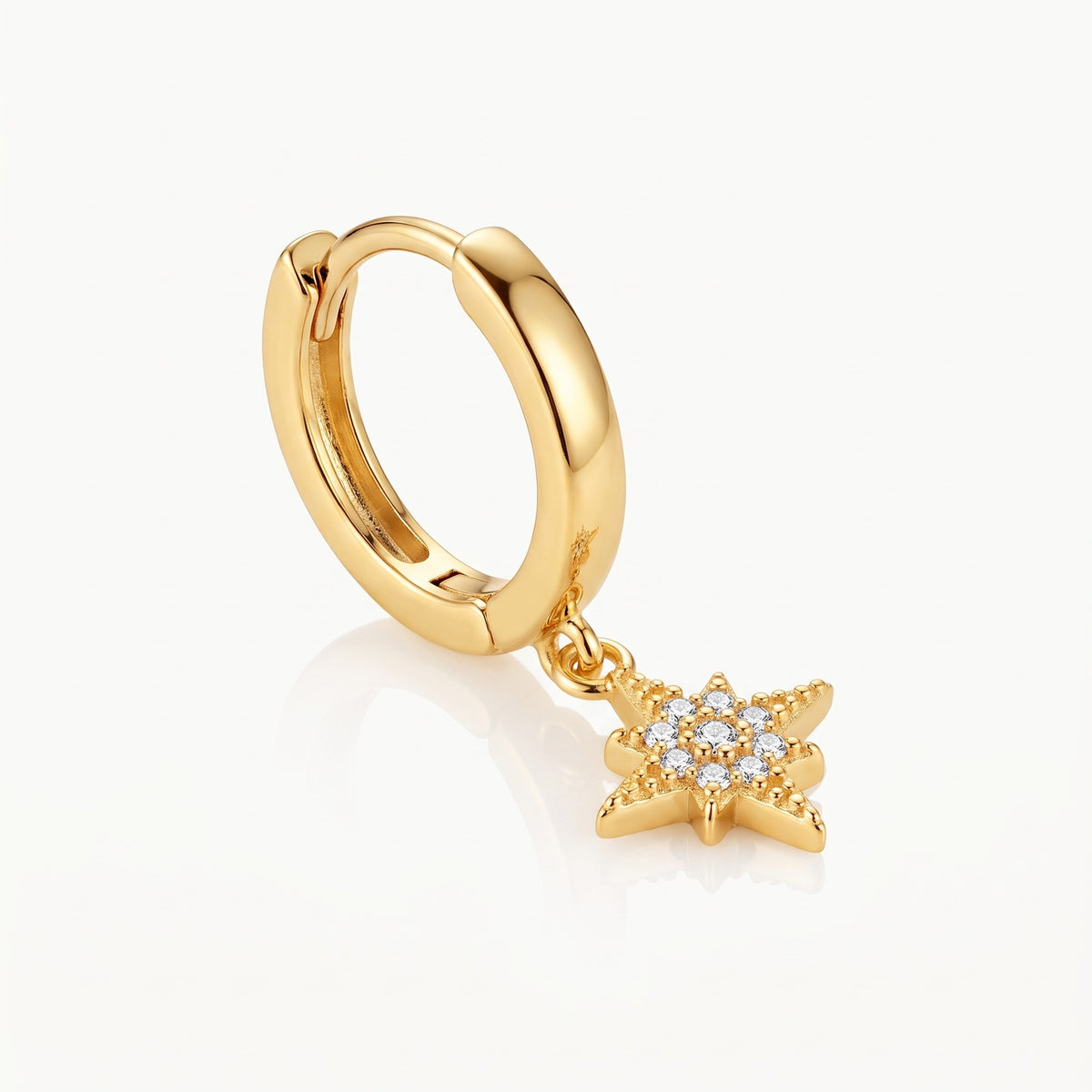 Close-up of a gold-tone charm and hinged huggie hoop