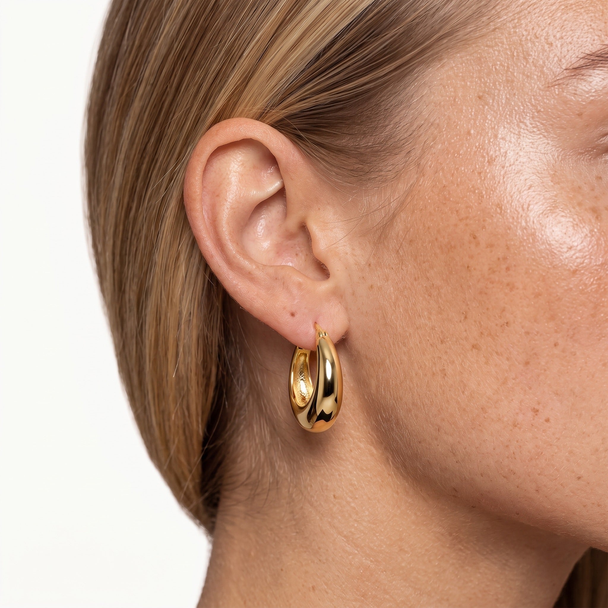 Gold-tone chunky tapered hoop earring worn on the ear
