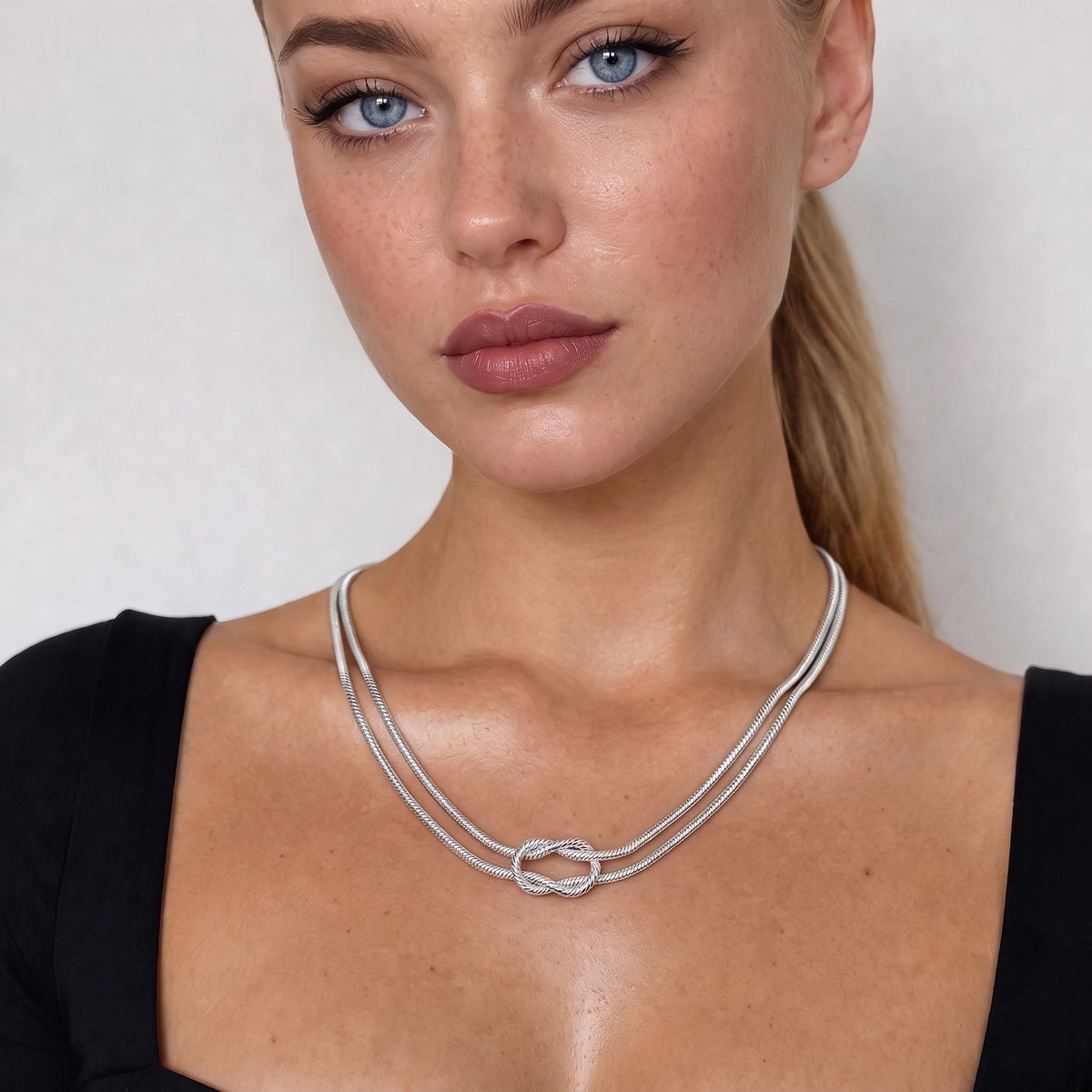 Silver-tone knot necklace worn at the collarbone