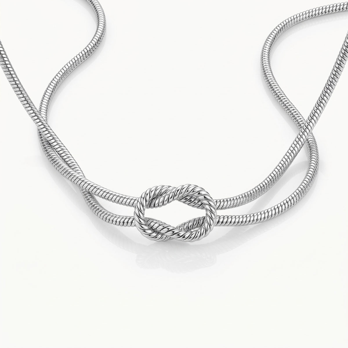 Silver-tone double snake chain crossing into a knot, seen from above