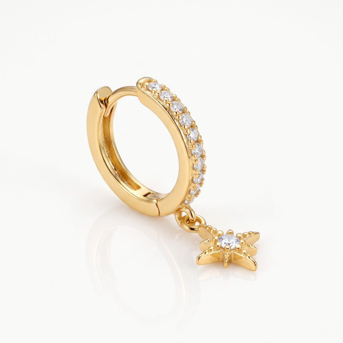 Close-up of the gold-tone star charm huggie hoop earrings