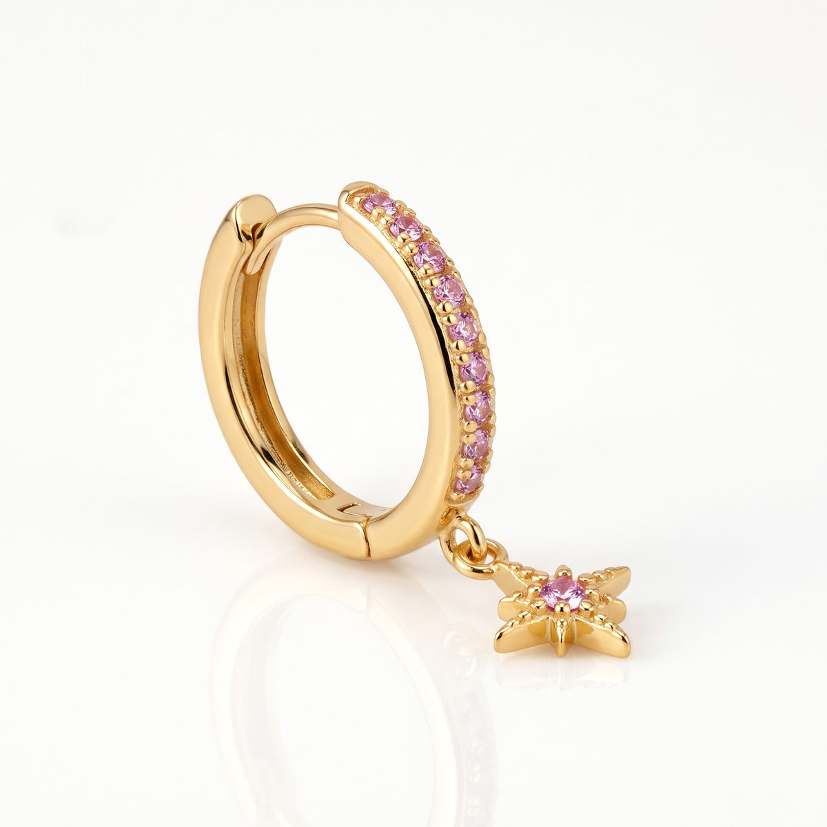 Close-up of the gold-tone star charm huggie hoop earrings with pink crystals