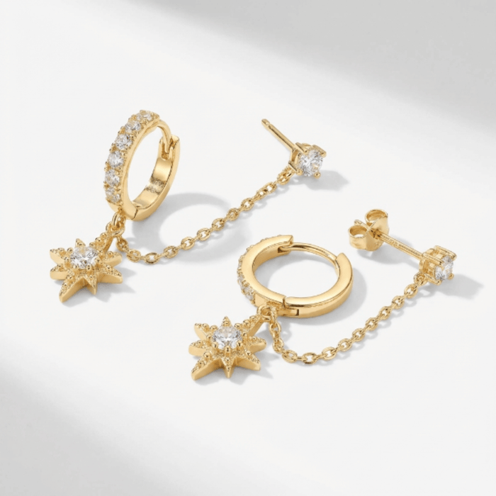 Gold-tone chained huggie earrings laid flat on a white surface
