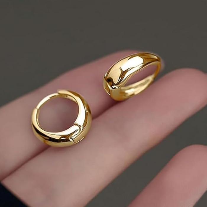 Pair of gold-tone chunky hoop earrings held between fingers
