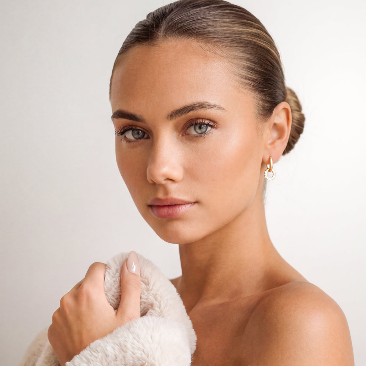 Model wearing gold-tone interlocking hoop earrings