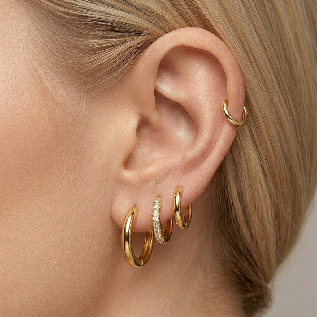 Gold-tone mini hoop earrings worn stacked in one ear