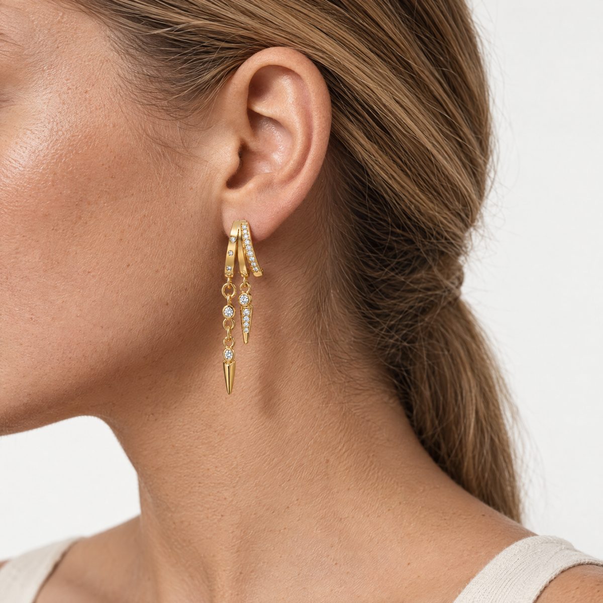 Gold-tone illusion hoop earrings with chain drops, worn