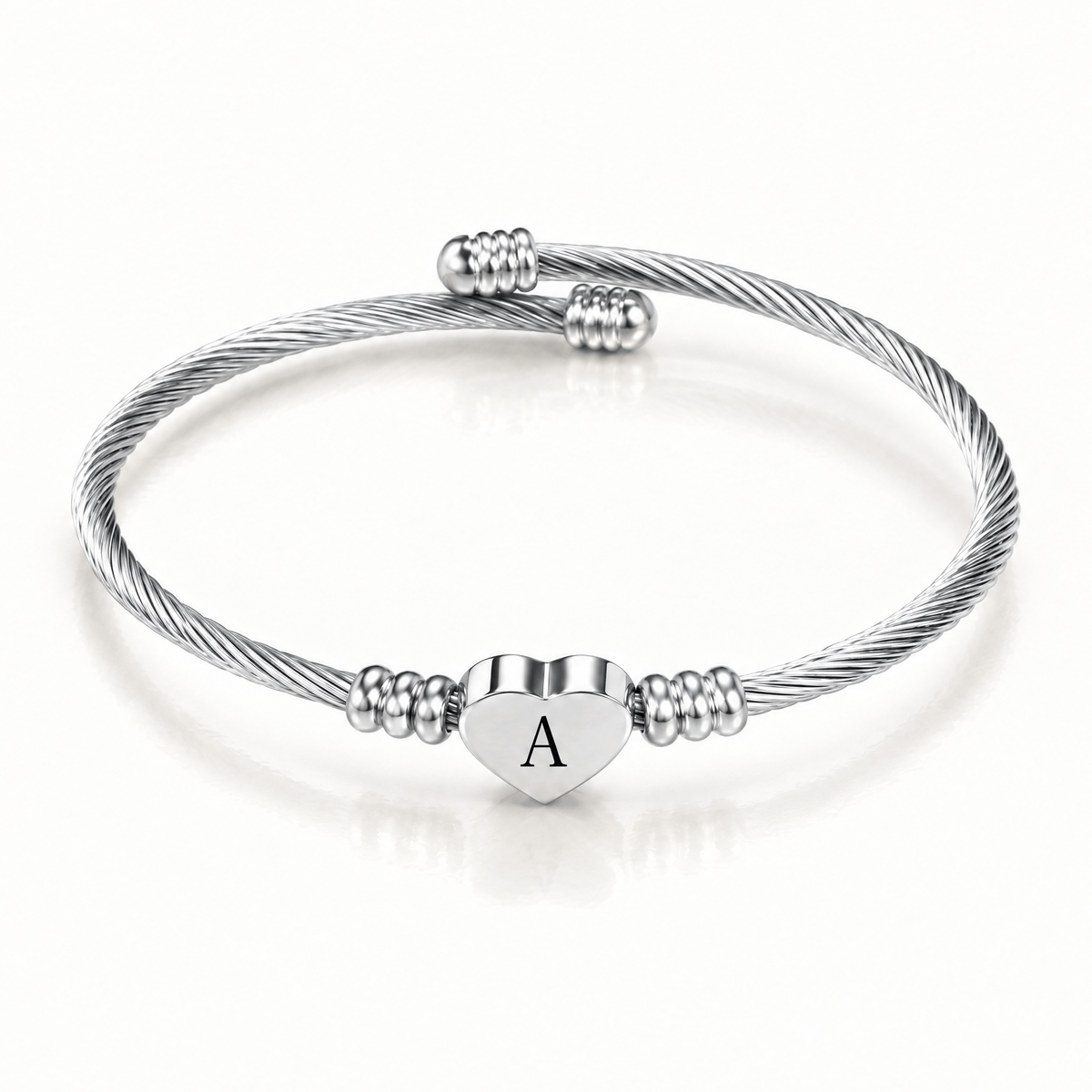 Silver-tone initial cuff bangle shown with different engraved letters on the heart charm