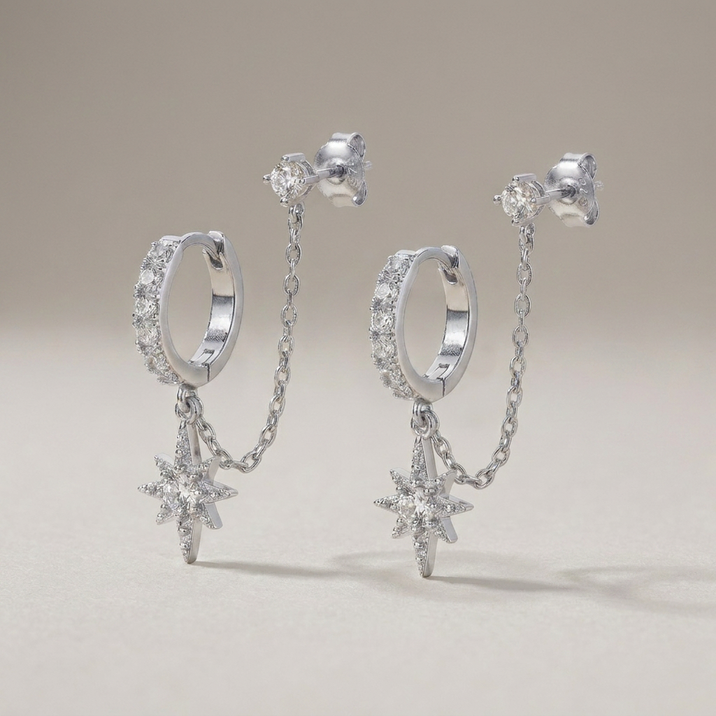 Silver-tone chained huggie earrings on a grey background