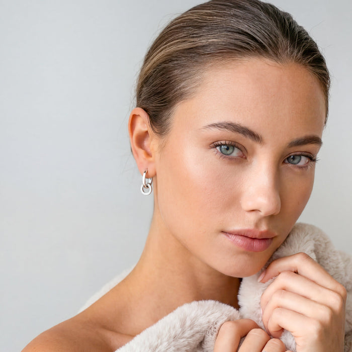 Model wearing silver-tone interlocking hoop earrings