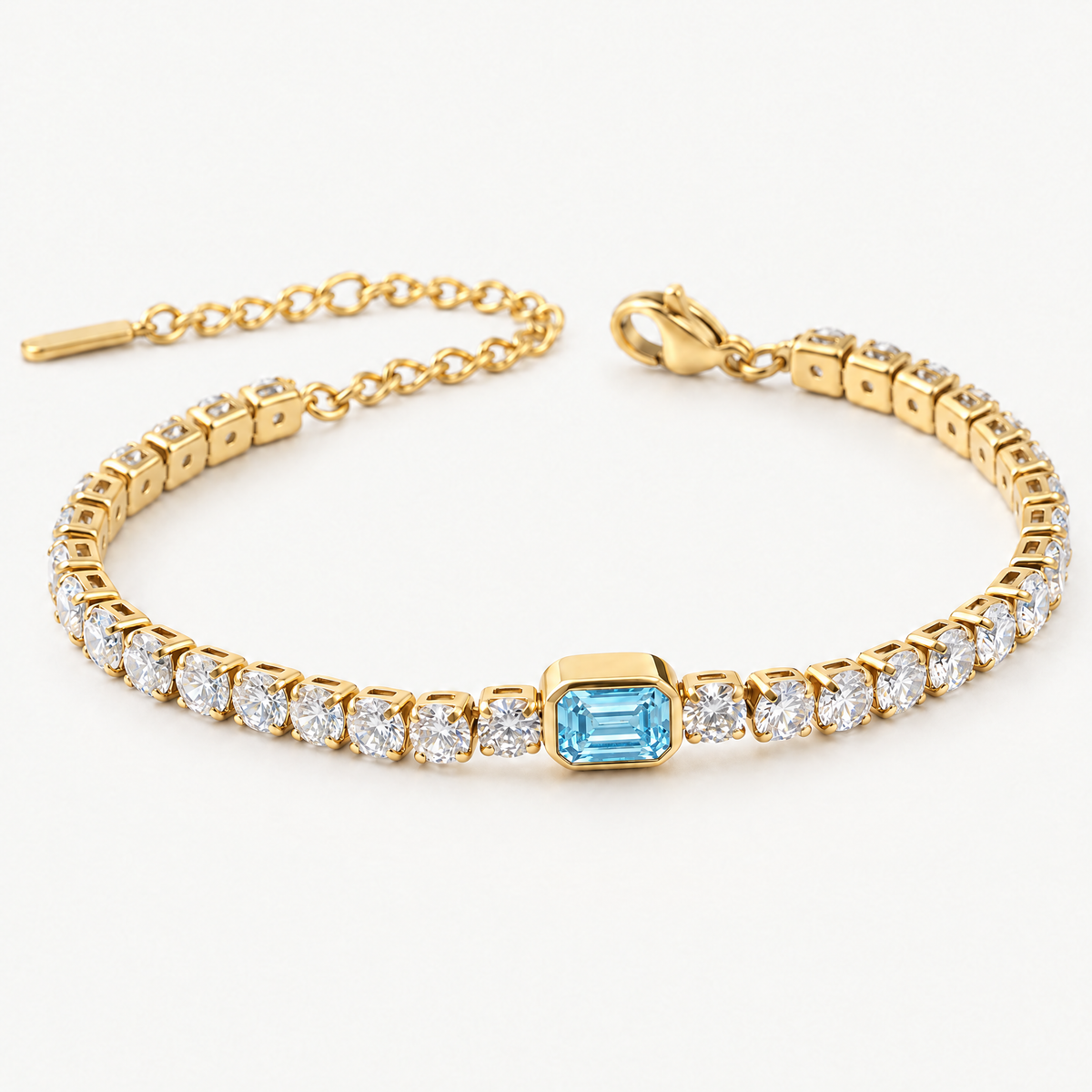 Gold-tone tennis bracelet with a blue emerald-cut centre stone, angled view