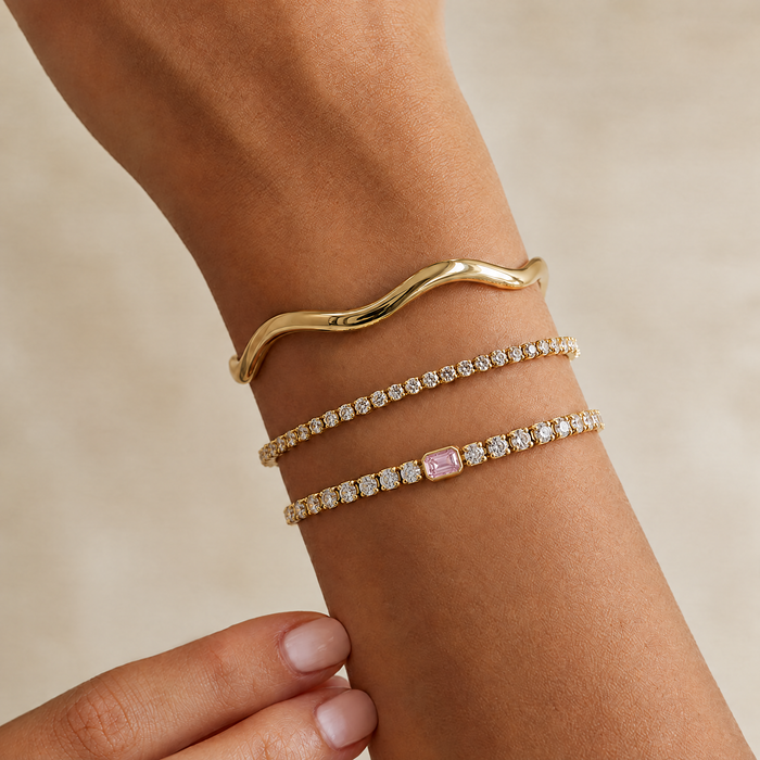 Tennis bracelet with pink centre stone on the wrist, stacked with a wavy bangle