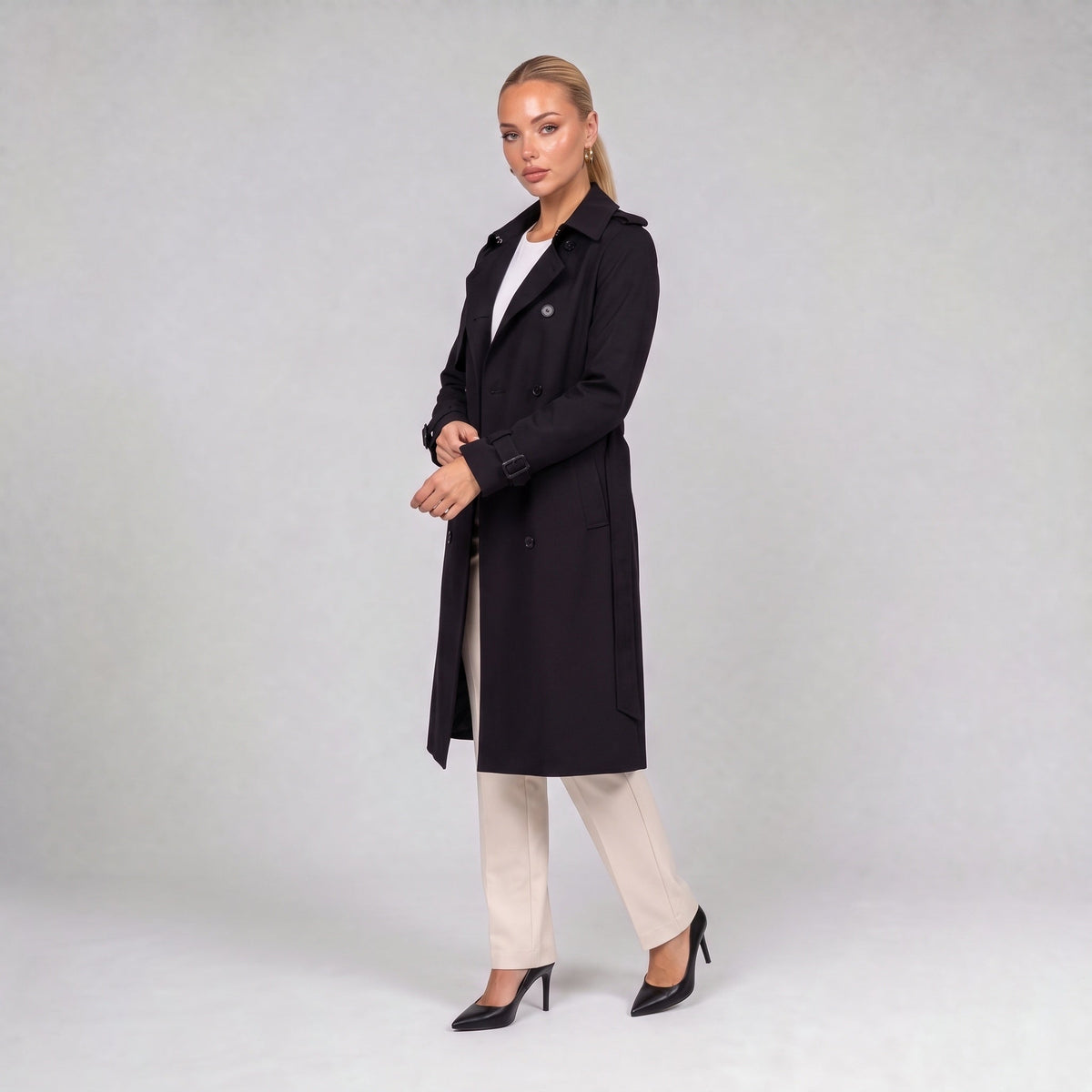 Black double breasted trench coat with belt, three quarter view on model