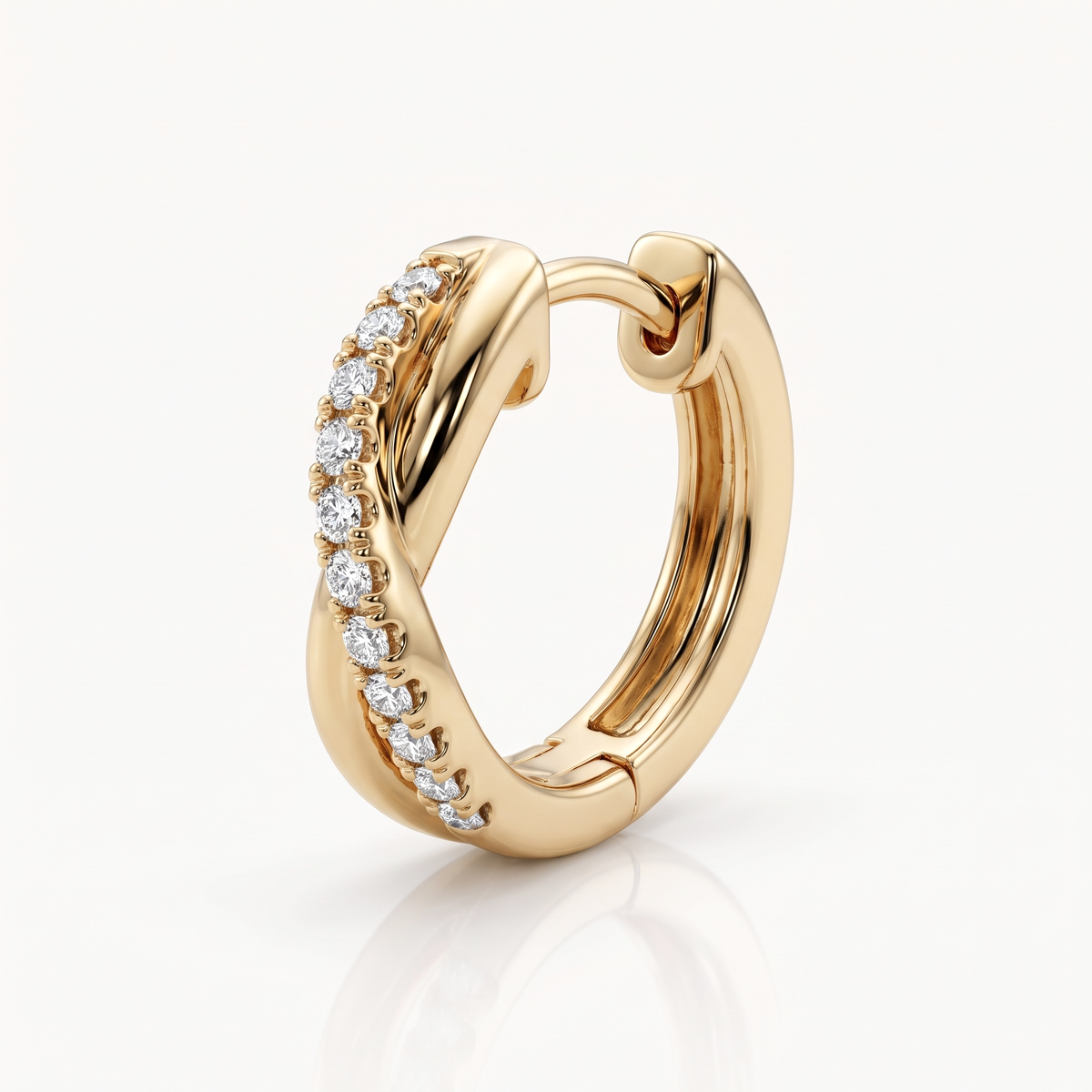 Close-up of a gold-tone twisted huggie hoop earring with its crystal-set band and hinged closure