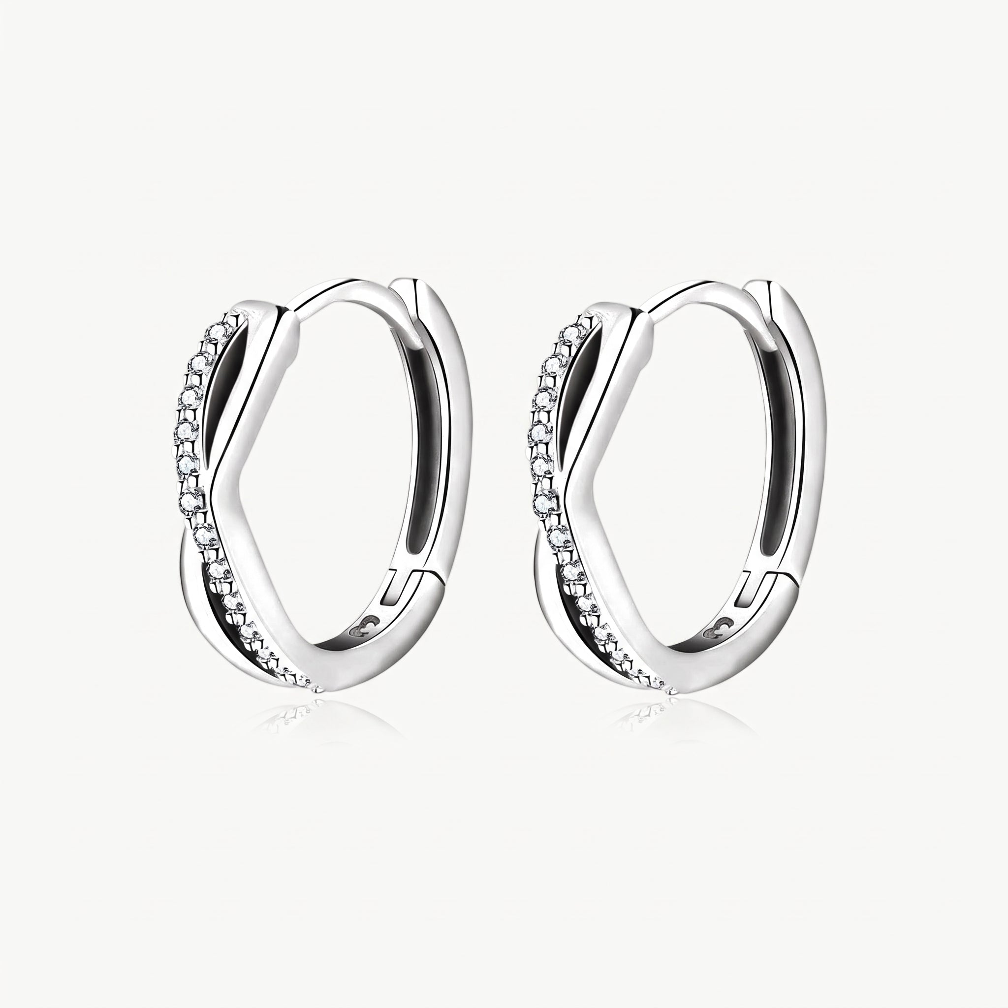 Silver-tone twisted crystal huggie hoop earrings, pair shown from the front