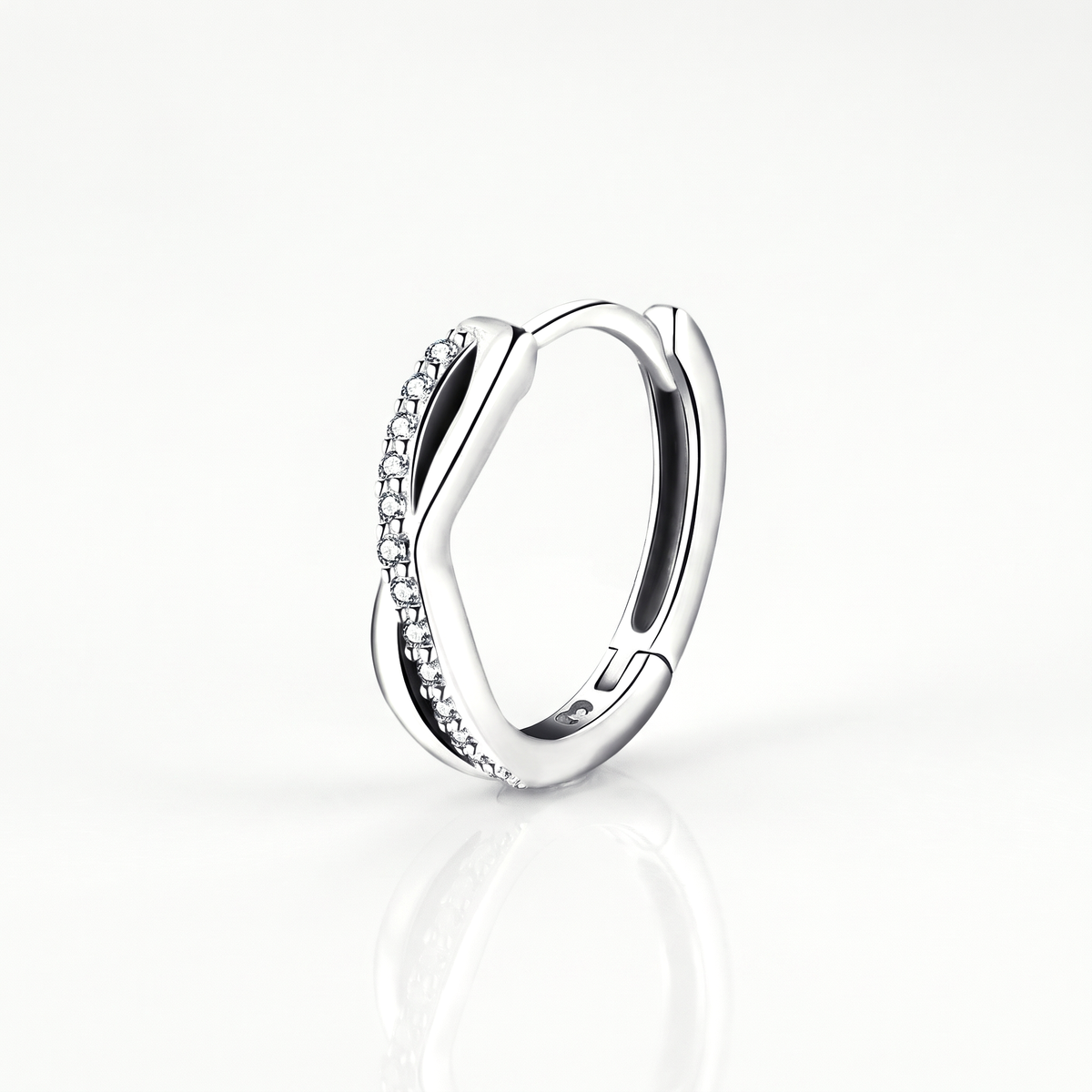 Close-up of a silver-tone twisted huggie hoop earring with its crystal-set band and hinged closure