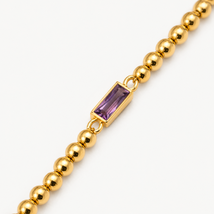 Close up of the purple baguette stone between gold-tone beads