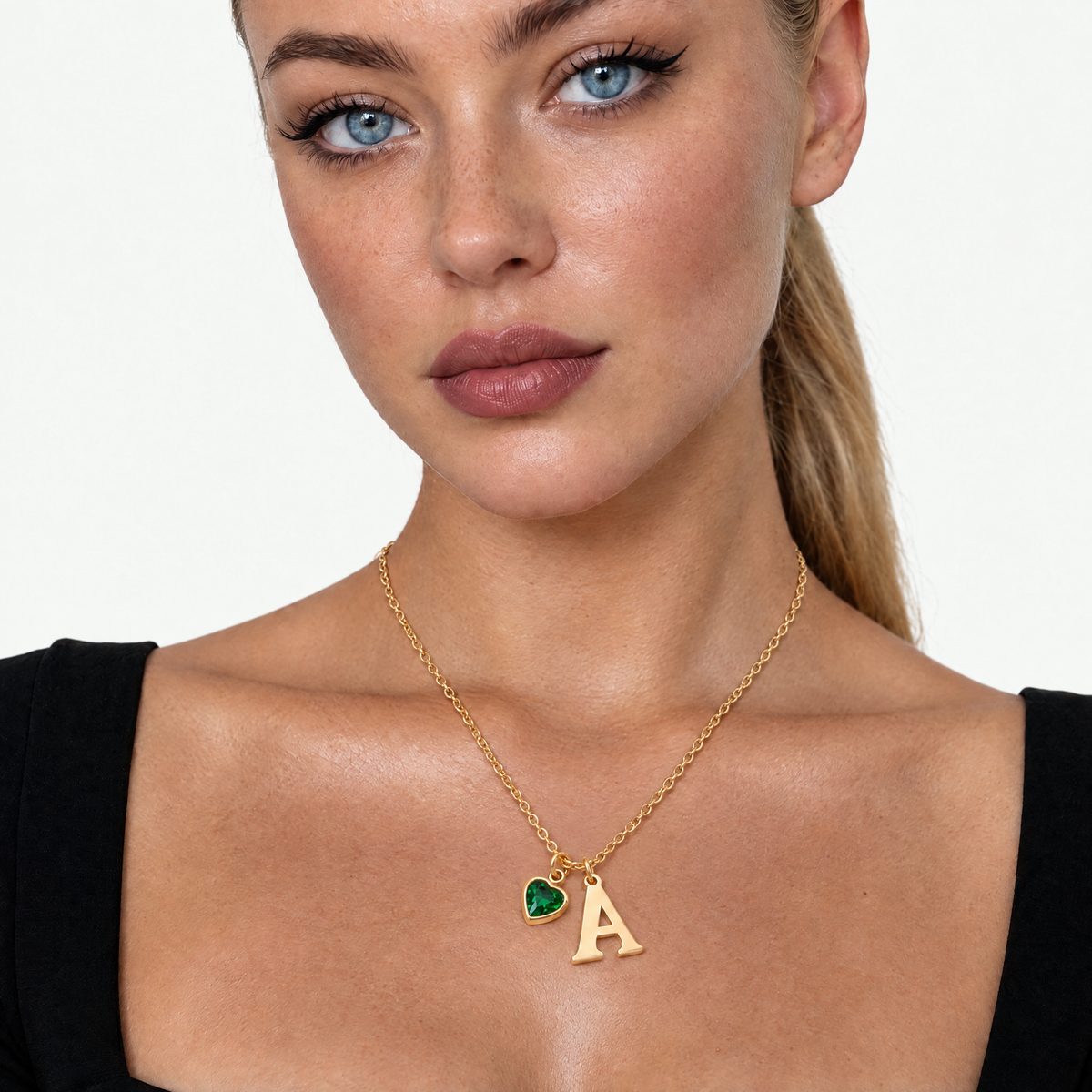 Model wearing the gold-tone initial necklace with a green heart birthstone, close up