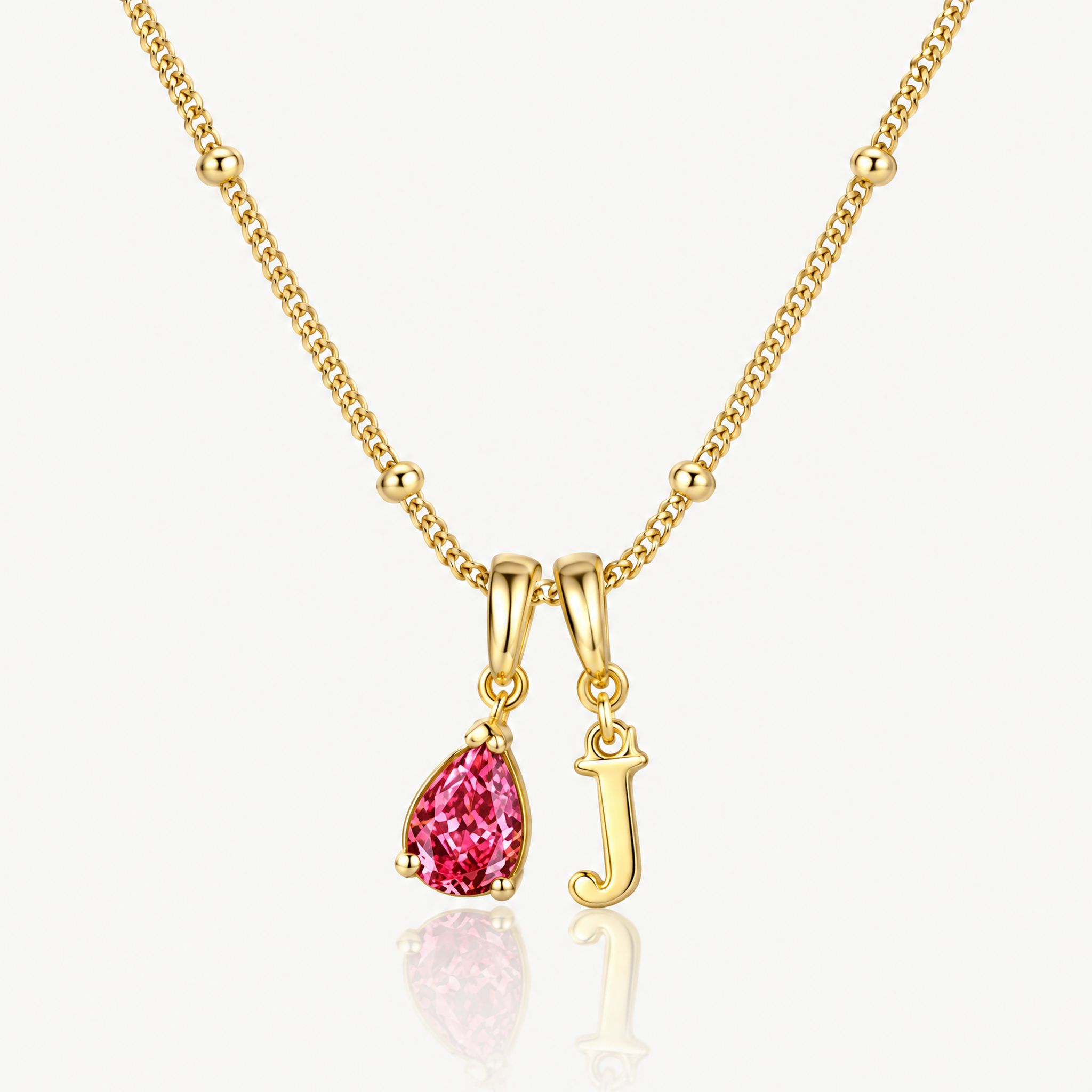 Gold-tone initial necklace with letter J pendant and pink crystal teardrop