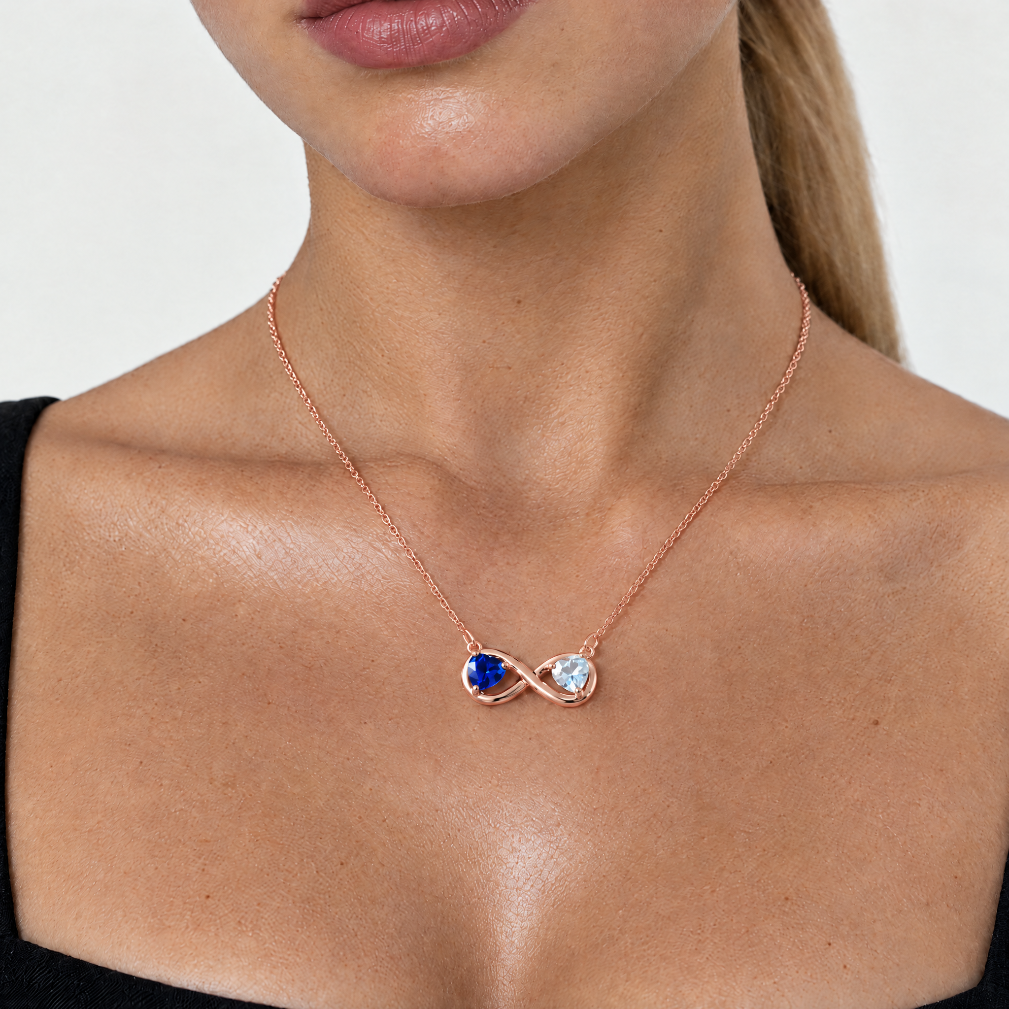 Model wearing the rose gold-tone infinity necklace with sapphire blue and clear crystal hearts