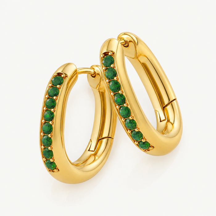 Pair of gold-tone oval huggie hoops with green stones, angled view